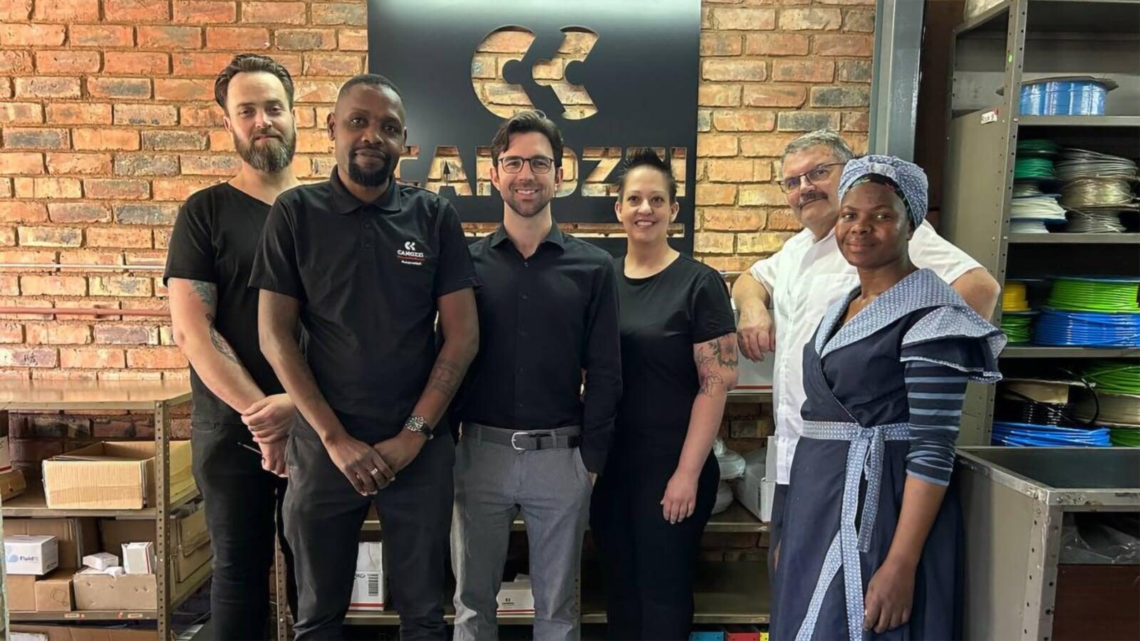 The Hydramatics team at the Sandton premises, in front of the Camozzi brand wall with stock shelving behind